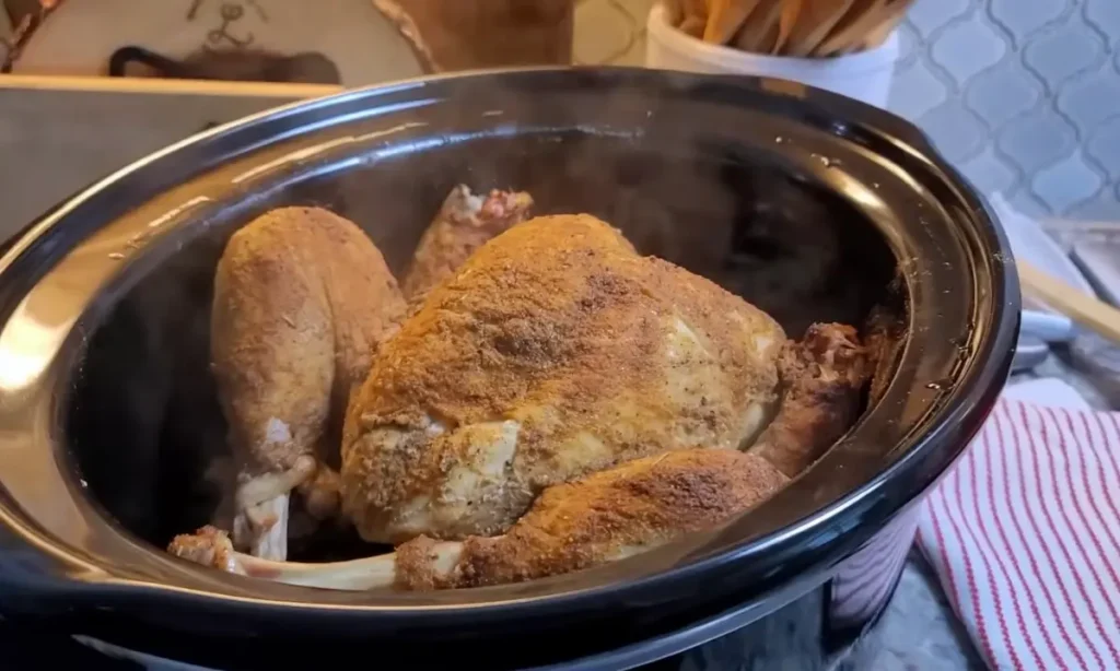 A golden-brown roasted chicken in a slow cooker, perfect for a warm and cozy Thanksgiving dinner.